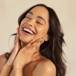 A woman smiling and gently touching her face, showcasing the results of a deep chemical peel treatment