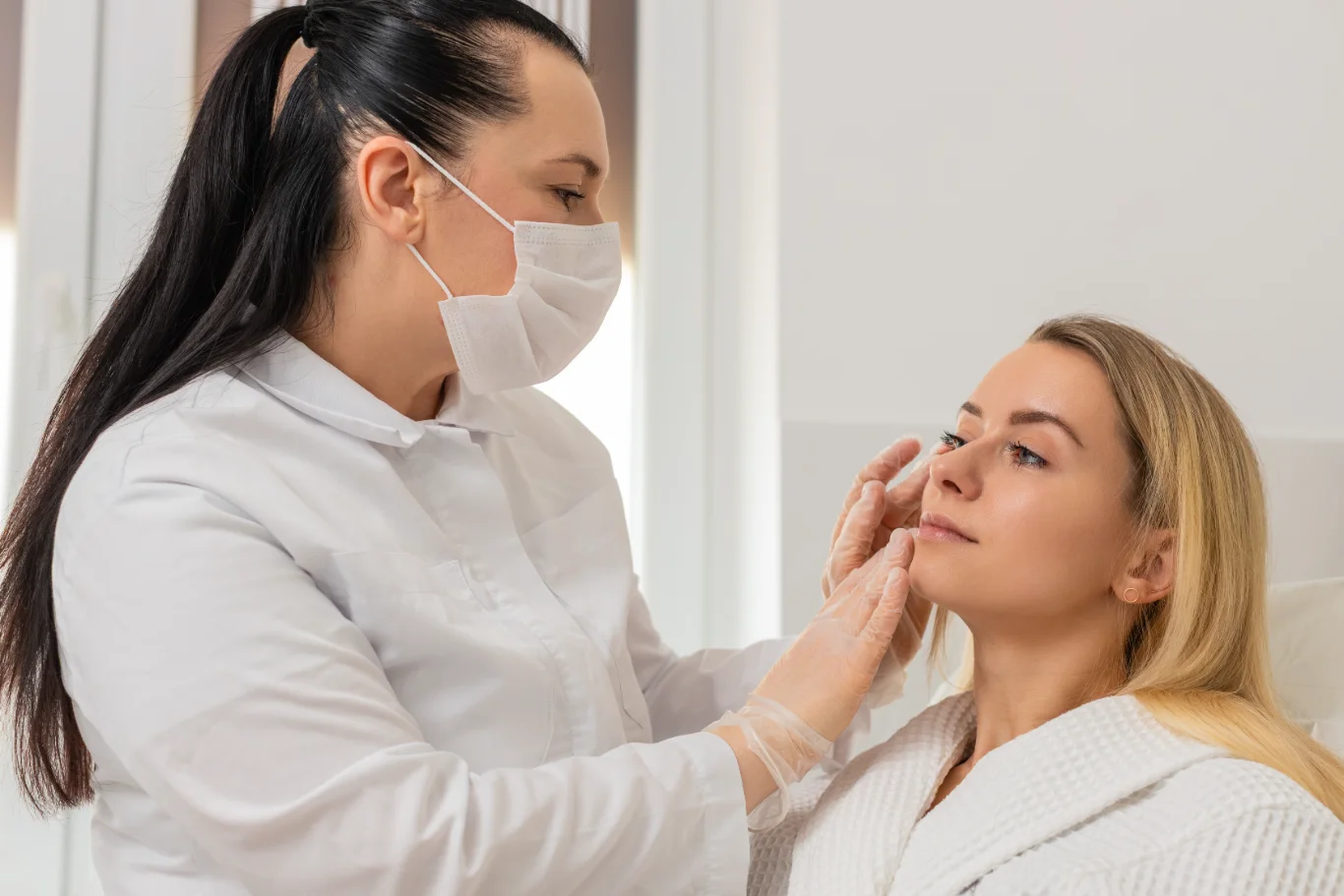 cosmetologist in mask gently inspects facial skin before treatment